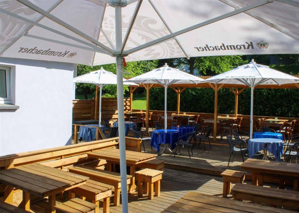 Das Bild zeigt die Terrasse mit Krombacher Schirmen und bei schönem Wetter