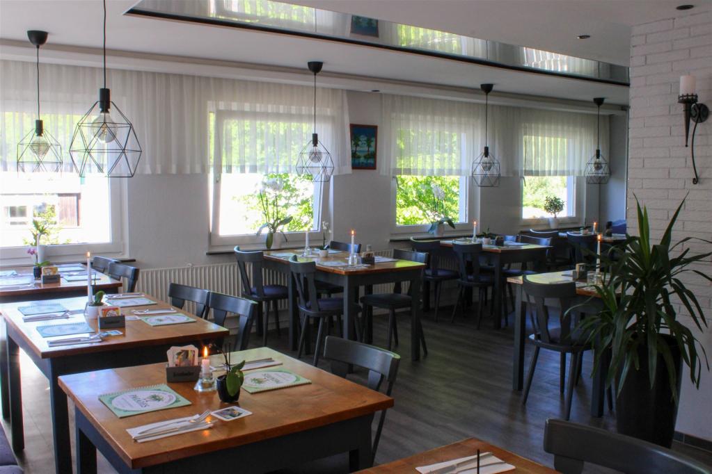 Das Bild zeigt den Innenraum des Restaurants mit brennenden Kerzen auf den Tischen, aus einer anderen Ecke fotografiert
